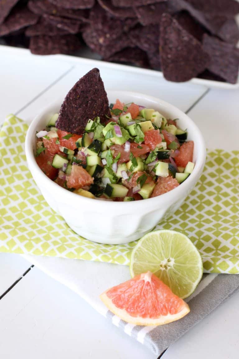 Grapefruit avocado salsa in small white bowl with blue corn tortilla chips on side