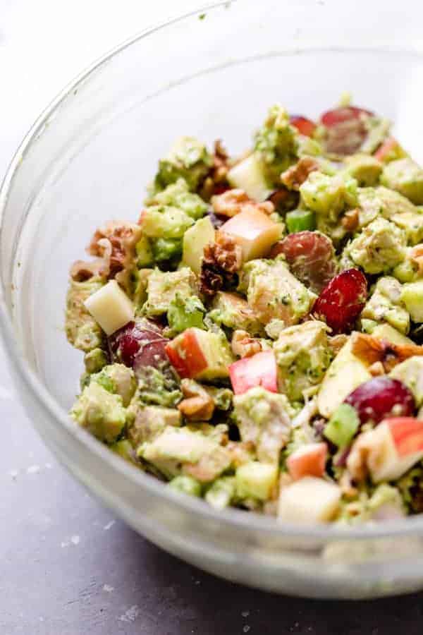 Close up photo of Avocado Chicken Waldorf Salad in a clear bowl.