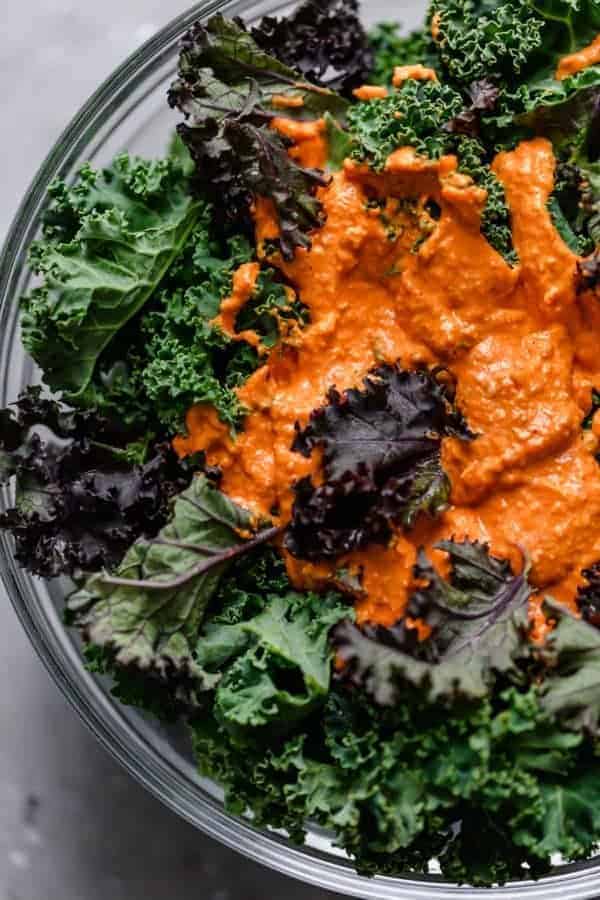 Overhead photo of bowl of kale chips with the sauce on top. 