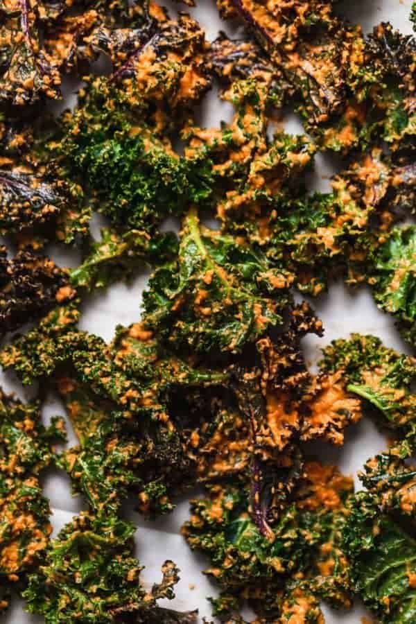Overhead photo of the sauce coated Cheese Pizza Kale Chips on a baking sheet, ready for the oven.