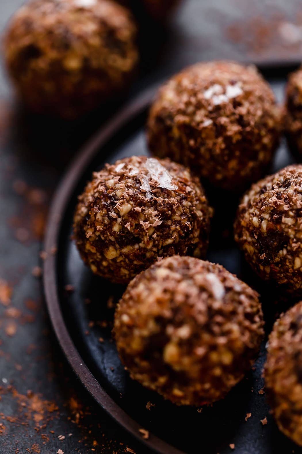 Close up view of cherry chocolate energy bites on a black plate. 