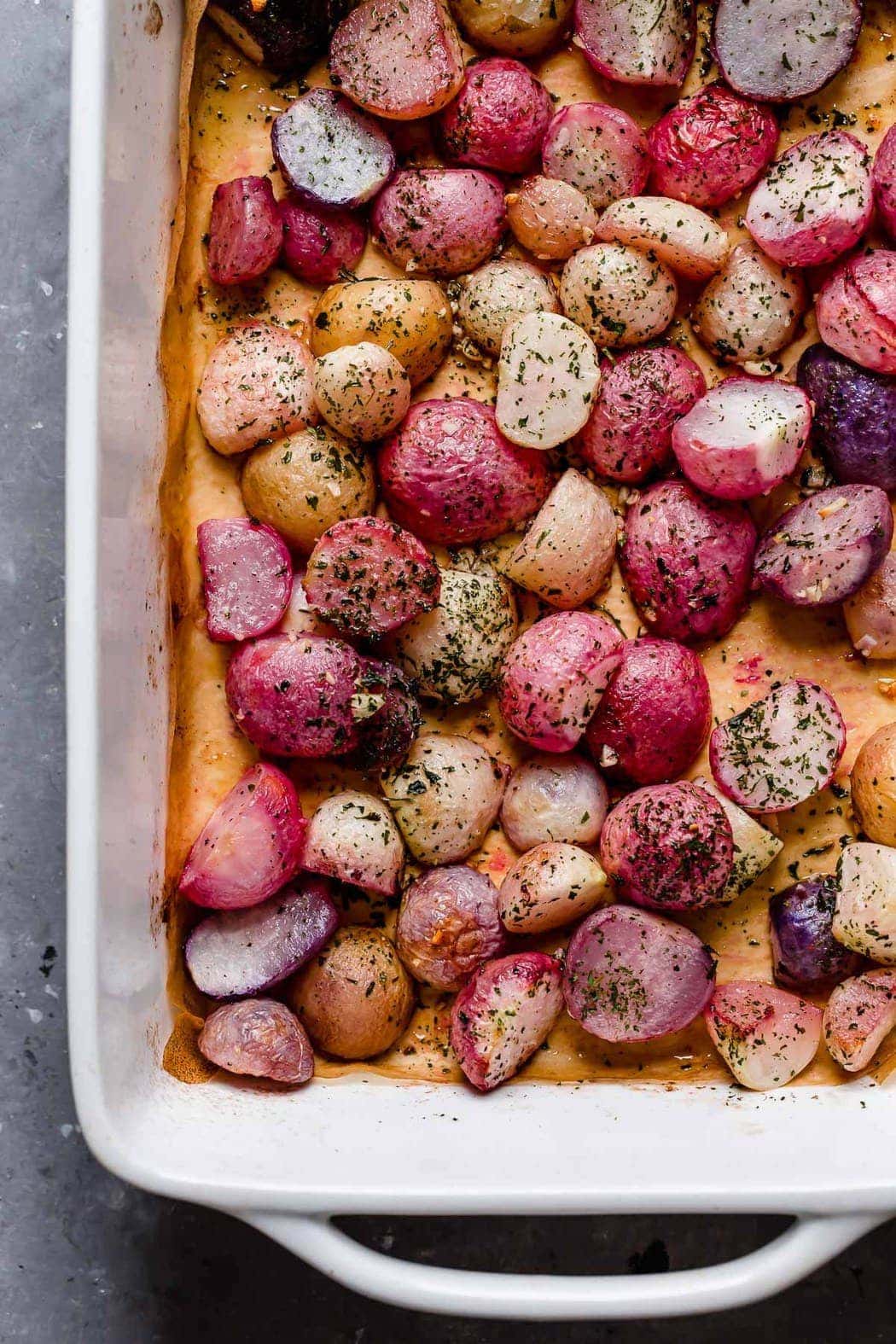 Garlic Roasted Radishes in a white baking dish just removed from the oven. 