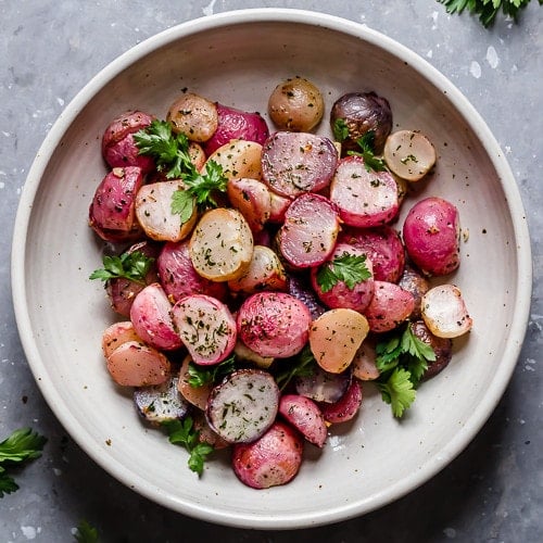 Overhead view garlic roasted radishes in white stone bowl