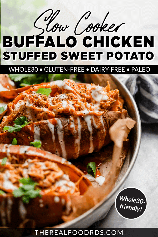 A shredded buffalo chicken stuffed sweet potato in a silver pan drizzled with ranch and topped with green onion and cilantro.