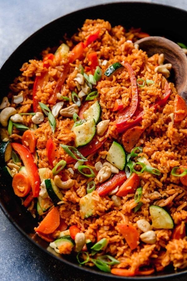 A skillet filled with Thai Coconut Curry Rice that is garnished with sliced green onions. 