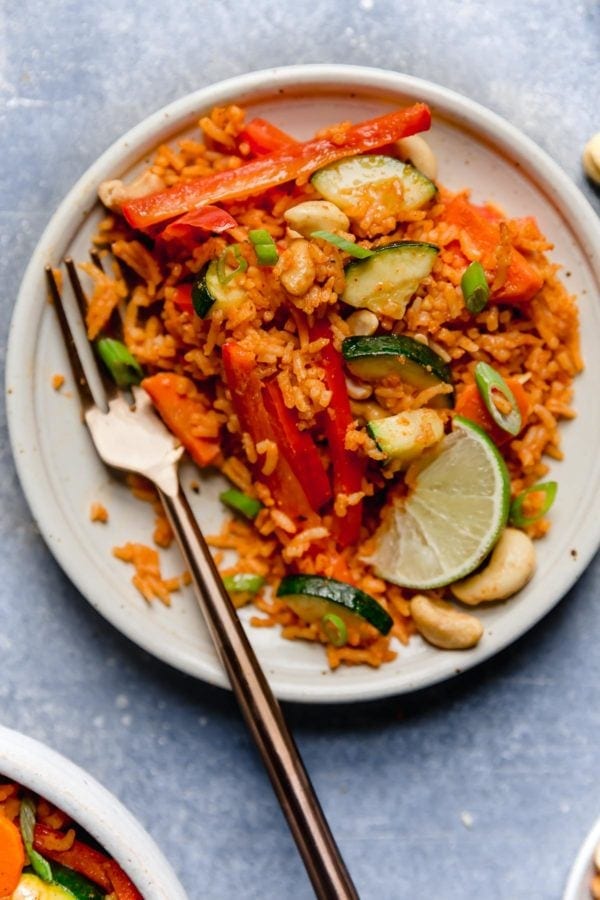 Overhead view of a small white plate with a gold fork next to a serving of Thai Coconut Curry Rice that appears to be in the process of being eaten.