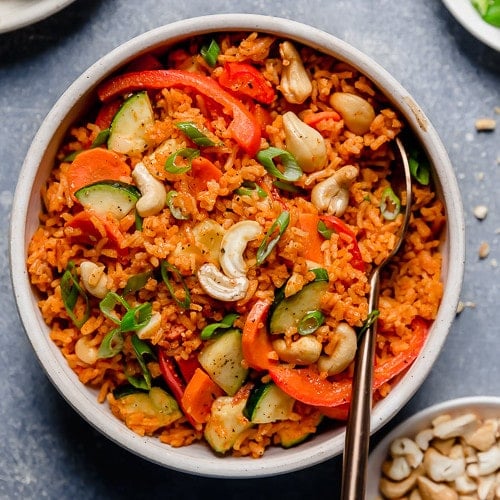 Overhead view of a white bowl filled with Thai Coconut Curry Rice with a gold fork in the bowl.