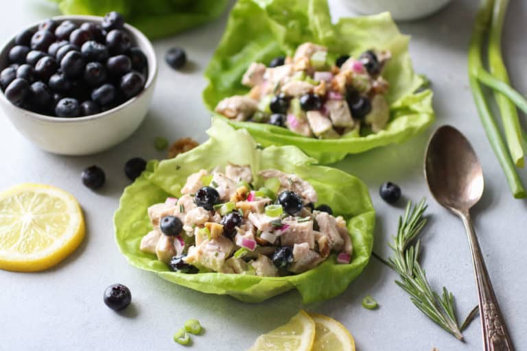 Close up view of Blueberry Chicken Salad with Rosemary on leaves of butter lettuce topped with green onions. 