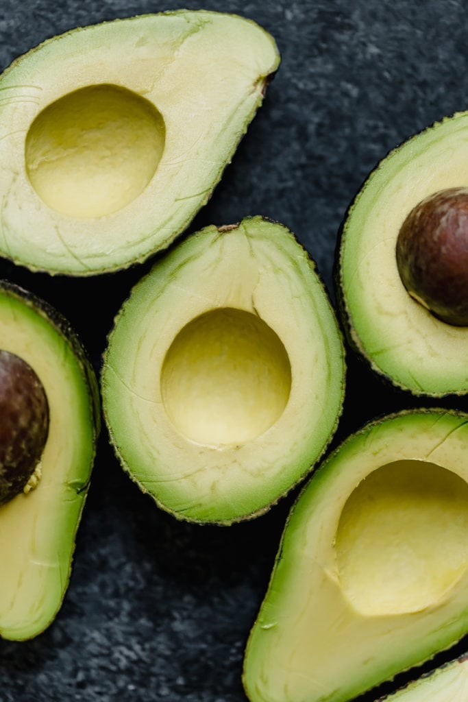 Overhead view avocado halves on dark background