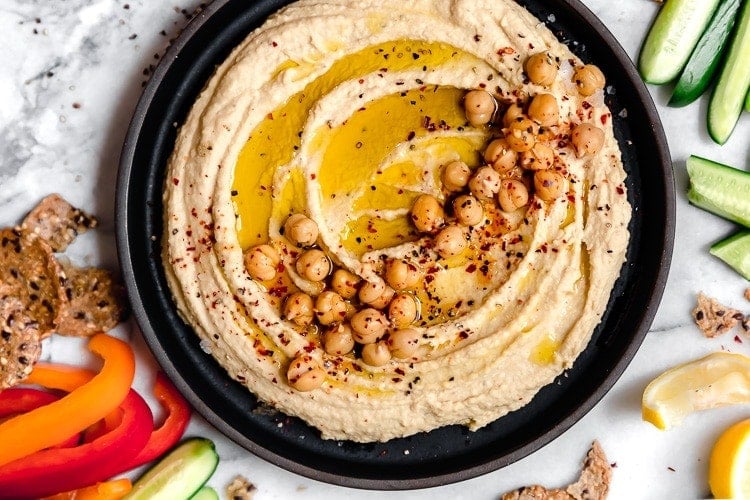 A bowl of 5-Ingredient Easy Garlic Hummus that is perfect to keep around as a meal prep snack during the week. 