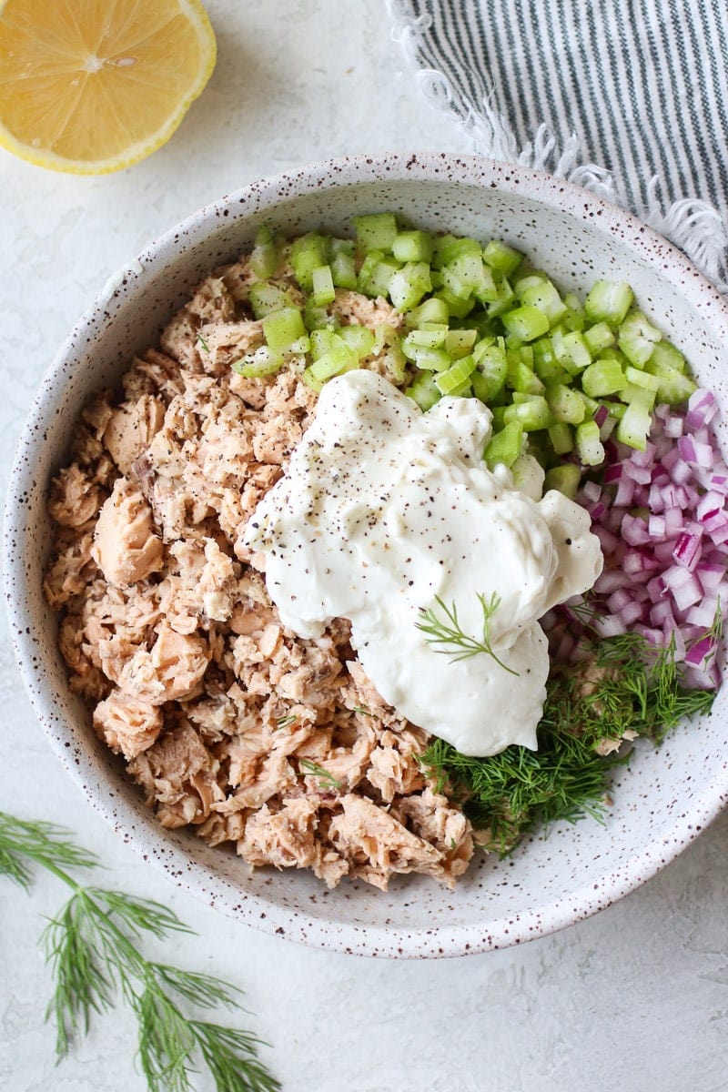 A speckled white bowl holding all of the fresh ingredients for the quick salmon salad.