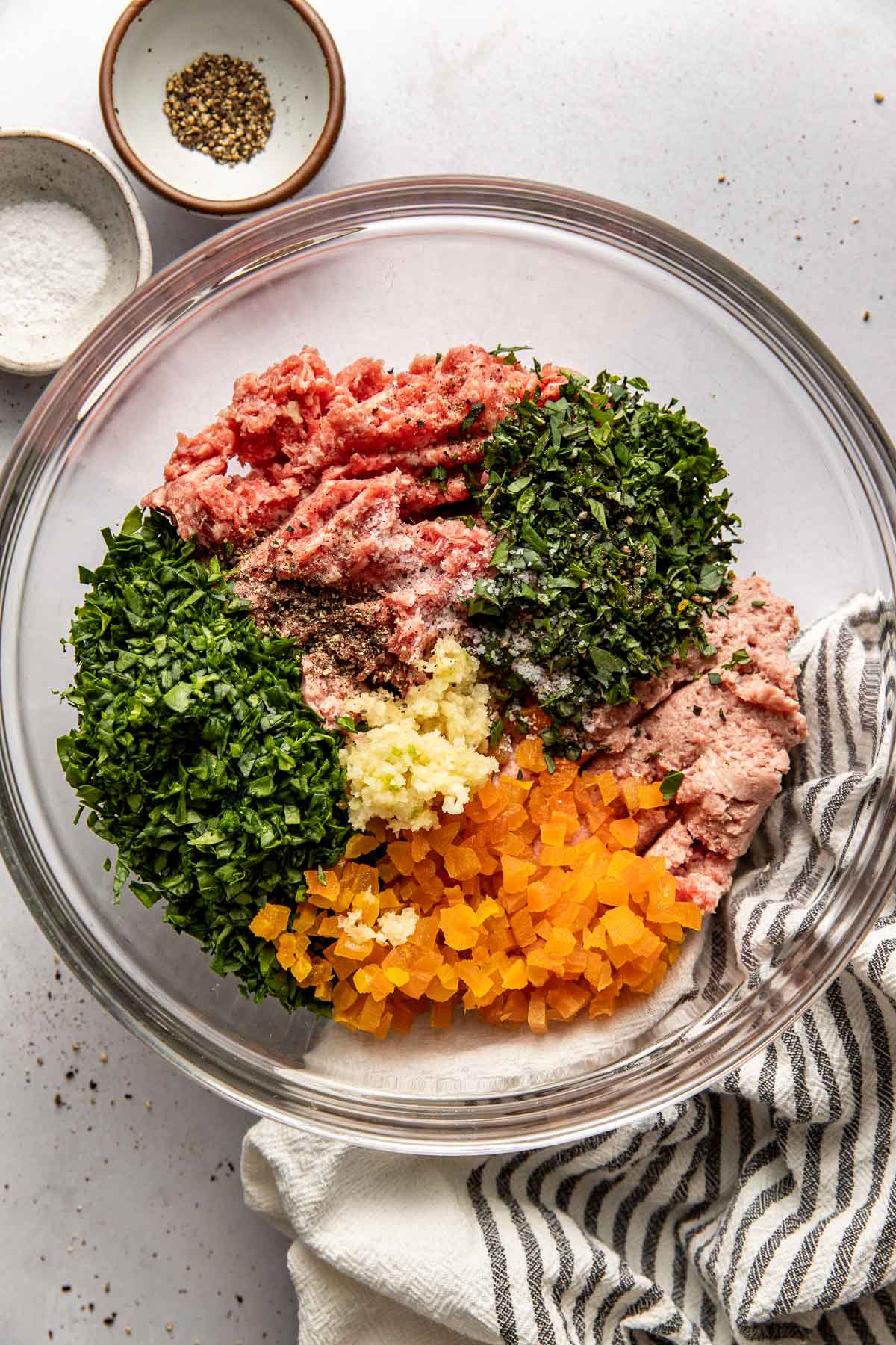 Overhead view of a glass bowl filled with Apricot Basil Breakfast Meatball ingredients ready for stirring. 