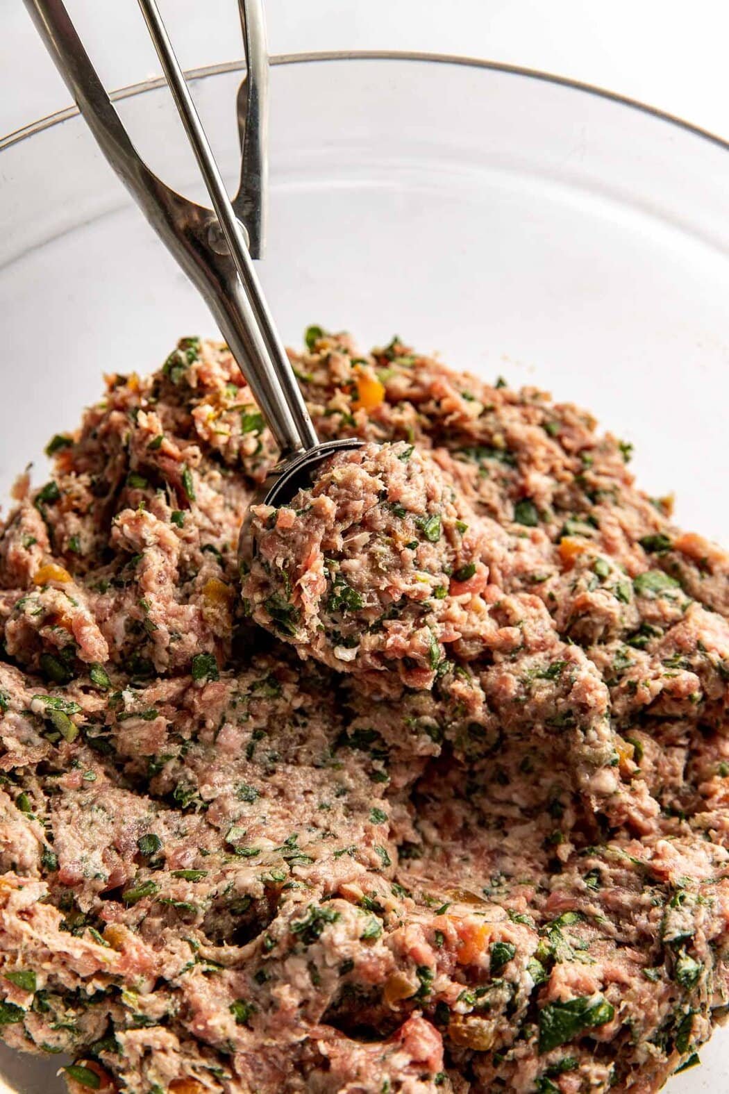 Close up view of a bowl of Apricot Basil Breakfast Meatball mixture being scooped with a spoon. 