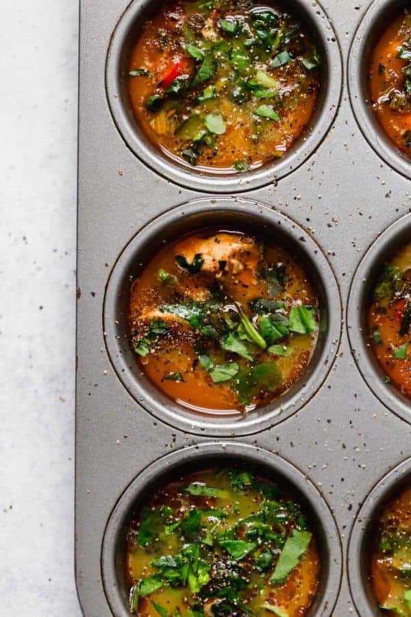 Overhead shot of Buffalo Chicken Egg Muffins in a muffin tin before they have been baked. 