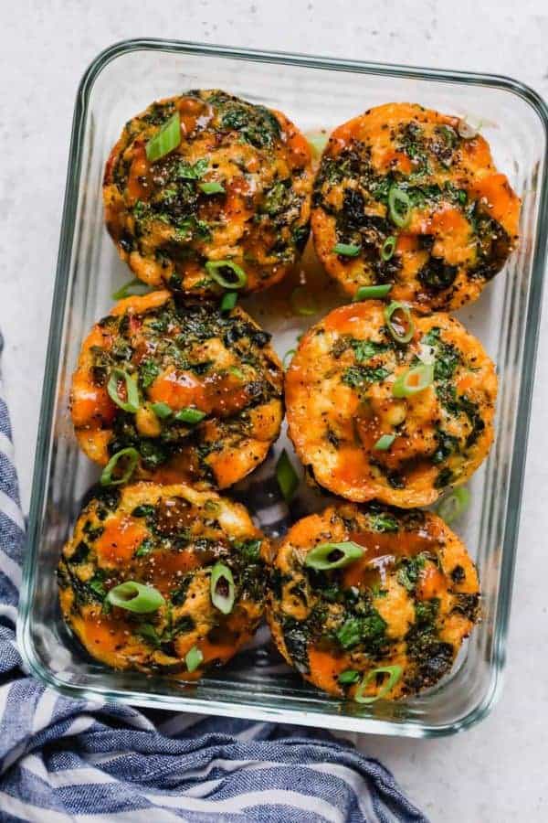 Overhead shot of six Buffalo Chicken Egg Muffins in a clear, rectangular glass storage container. 