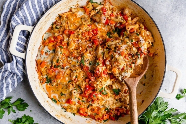 Creamy buffalo chicken casserole with red peppers in skillet.
