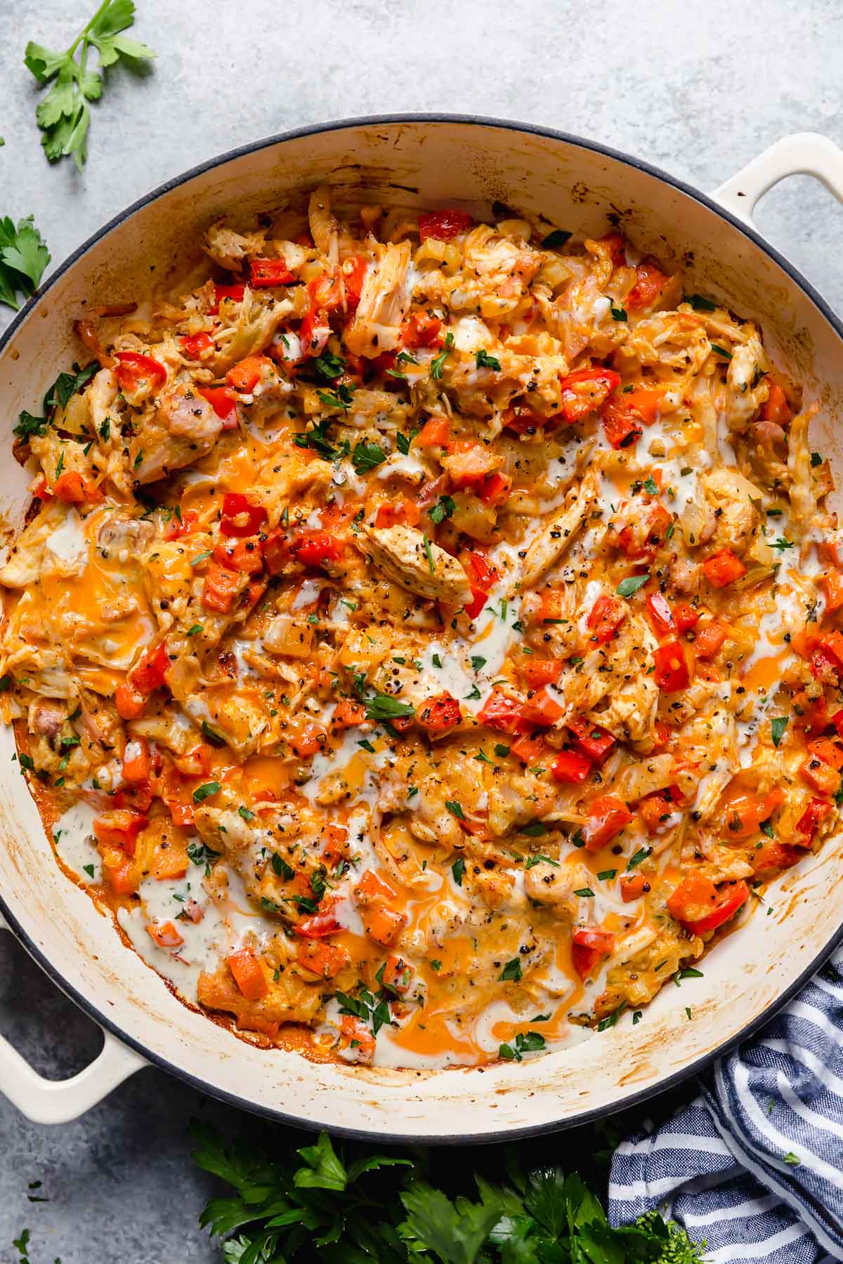 Overhead view baked creamy buffalo chicken casserole in white pan with ranch drizzled over top.