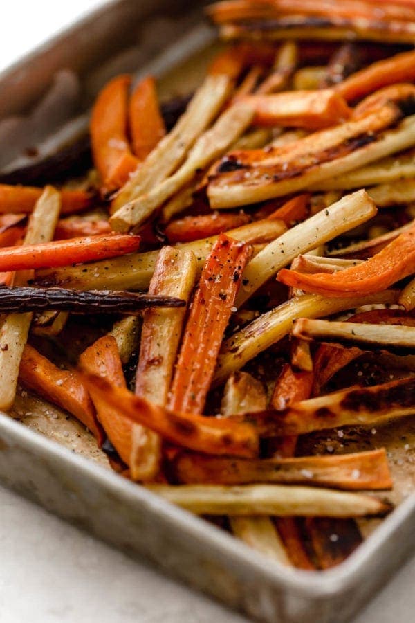 Close up of a sheet pan with garlic roasted root vegetable fries hot from the oven. 