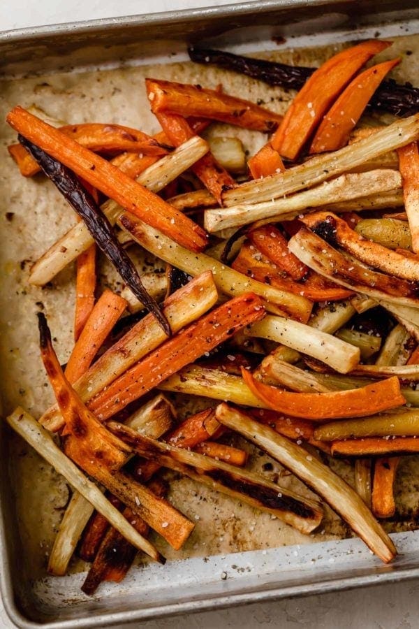 Overhead view of a pan of garlic roasted root vegetable fries sprinkled with coarse sea salt. 