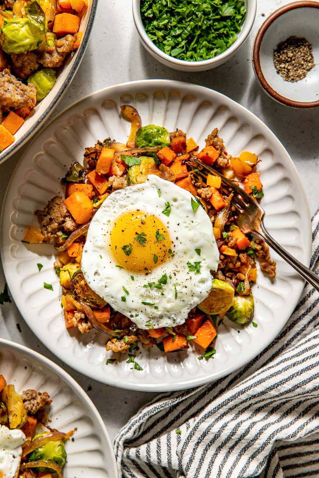 Overhead view of a plate of Sweet Potato Hash with Sausage topped with a fried egg. 