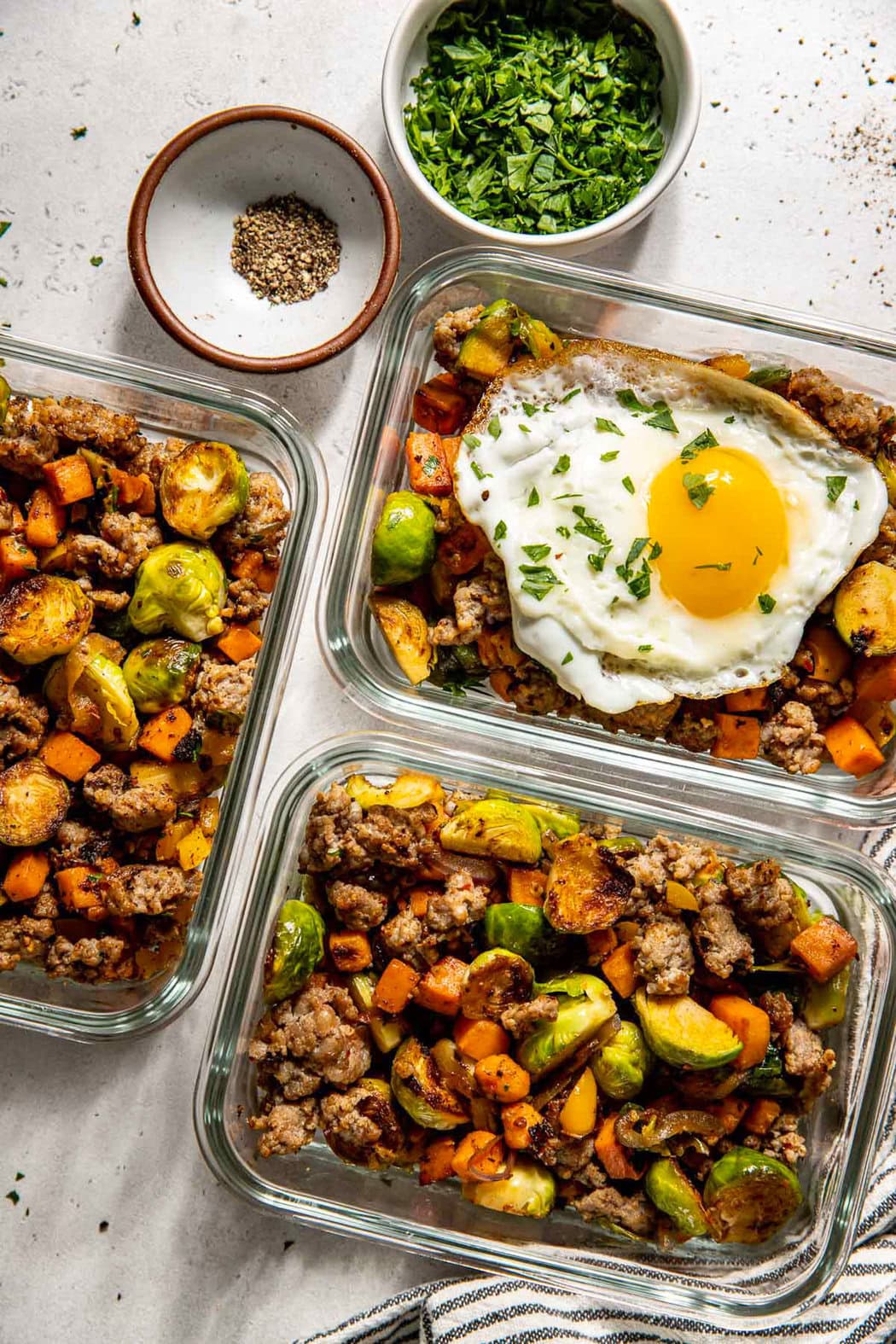 Overhead view of glass storage containers filled with Sweet Potato Hash with Sausage ready for meal prep.