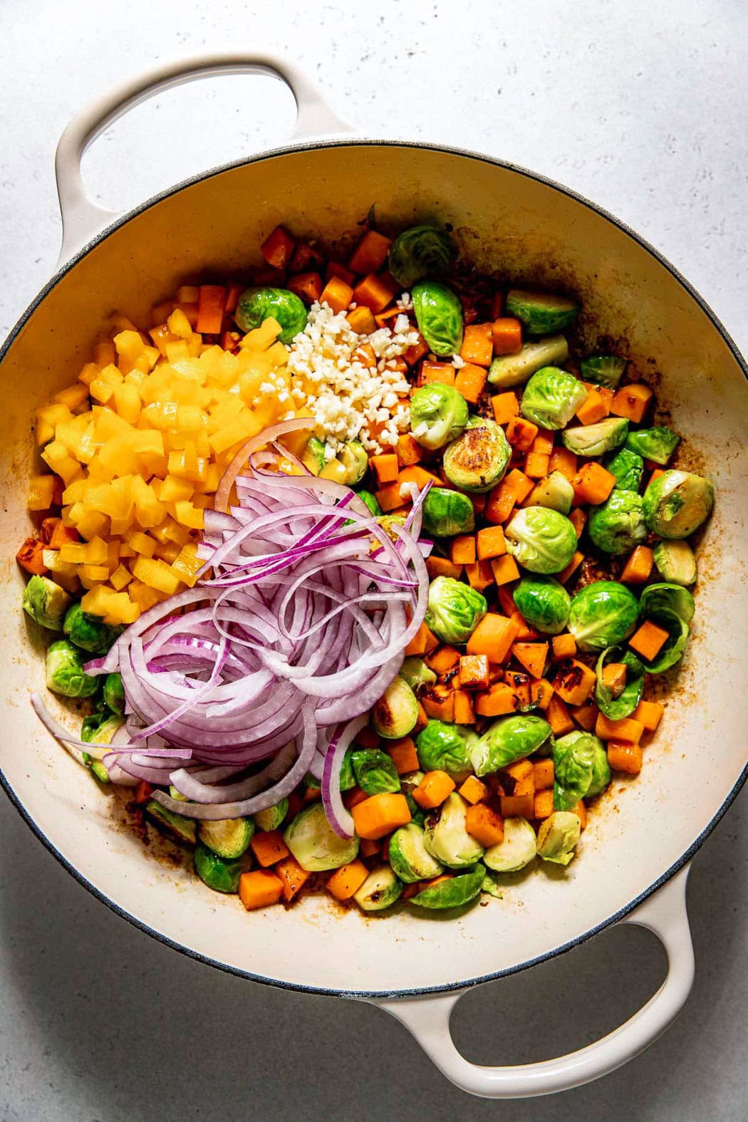 Overhead view of a skillet filled with ingredients for Sweet Potato Hash with Sausage ready for sauteing. 