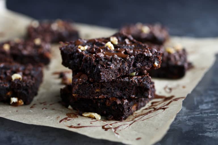 Three grain-free sweet potato brownie squares topped with walnuts stacked up on each other.
