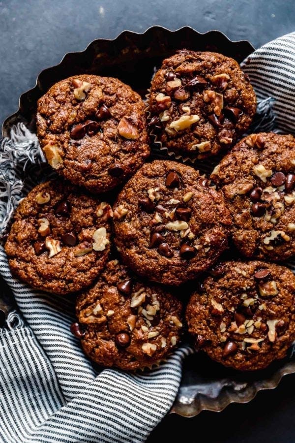 A fluted tin tray filled with Grain-Free Sweet Potato Banana Nut Muffins on a medium gray surface. 