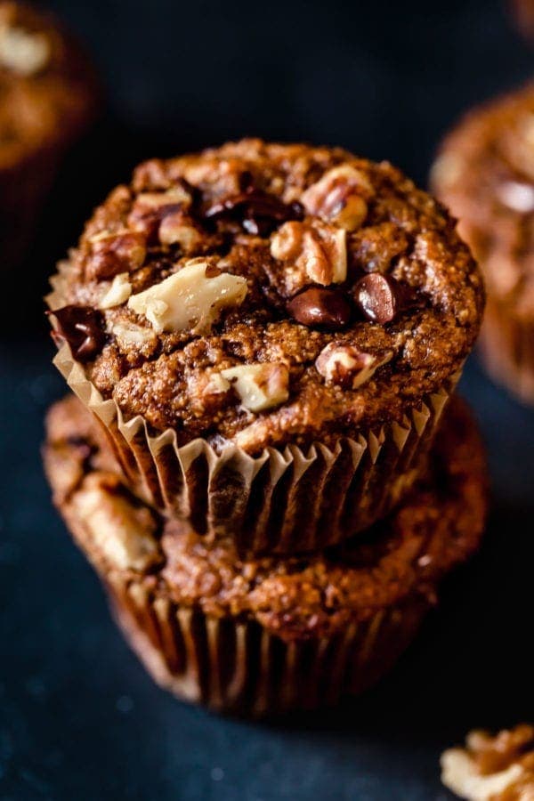 Close up of two Grain-Free Sweet Potato Banana Nut Muffins stacked on top of one another (with chocolate chips and walnuts on top).