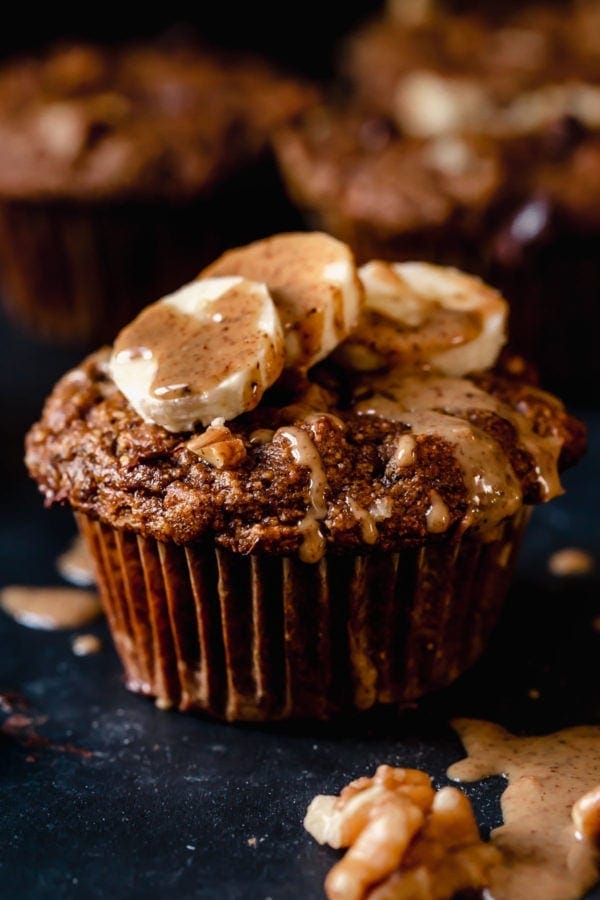 A grain-free sweet potato banana nut muffin topped with banana slices and almond butter.