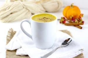 Pumpkin Spice Chai Tea in a white mug on a white napkin with a silver spoon resting beside the mug