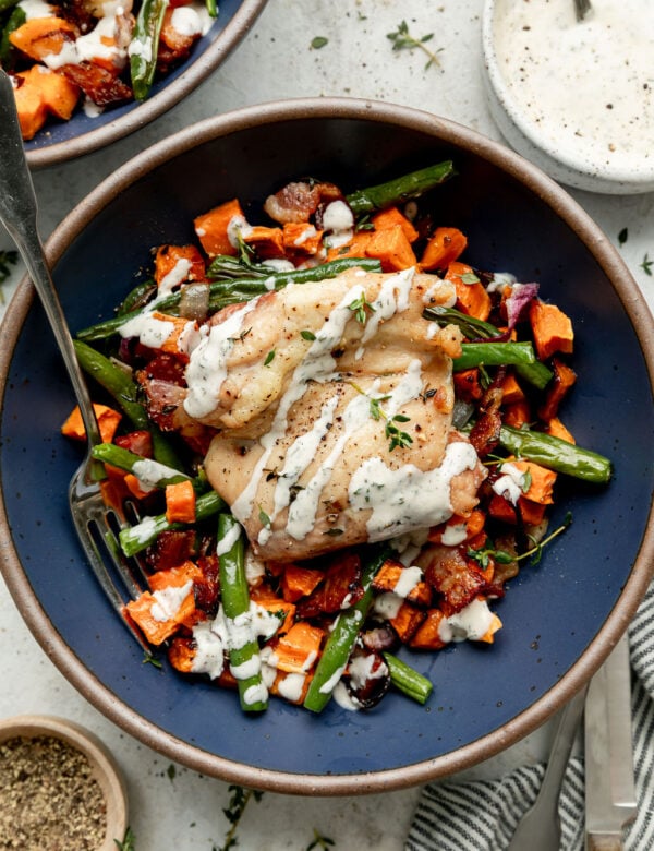 Overhead view blue bowl with serving of chicken bacon ranch served over roasted vegetables.