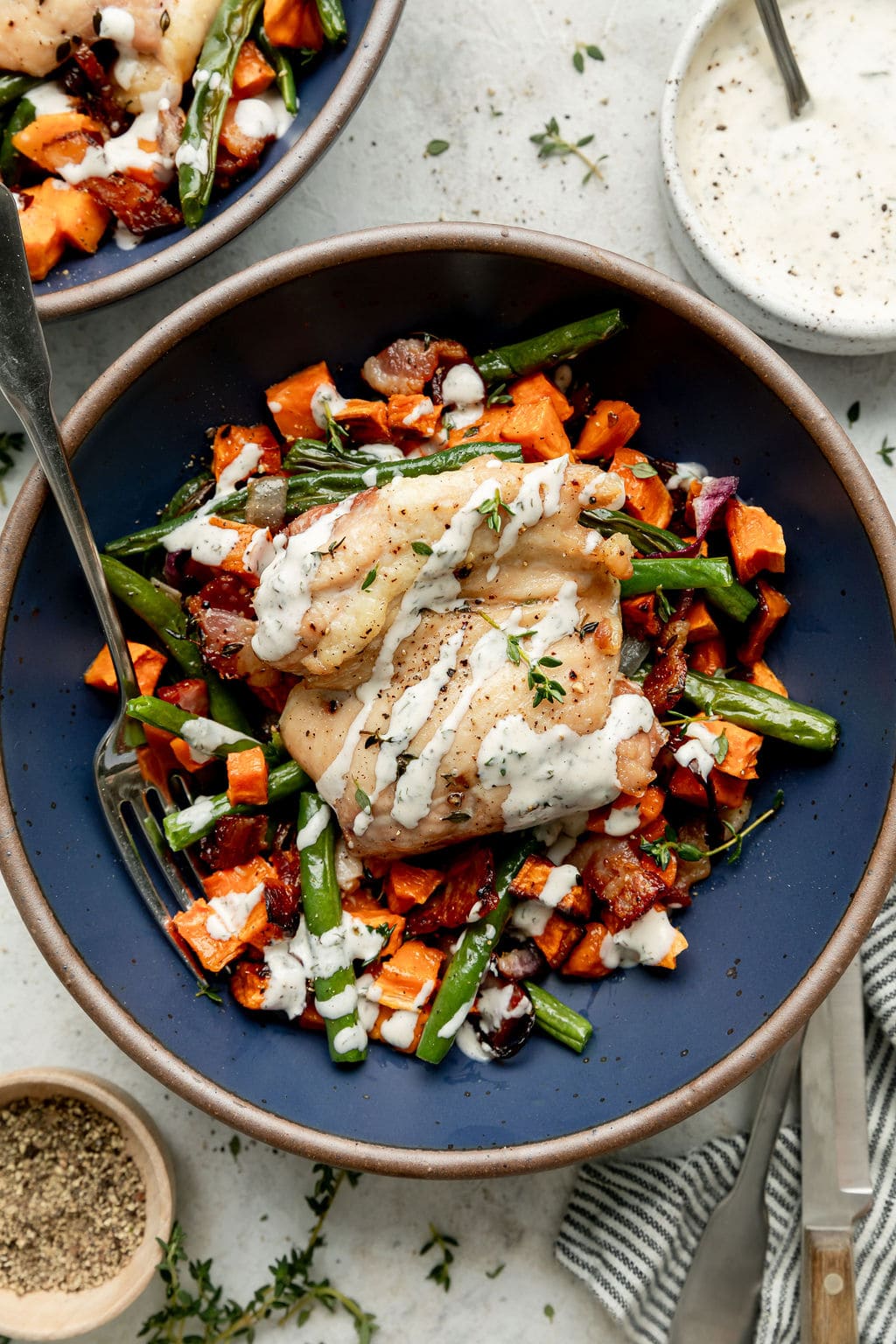 Overhead view of a plate filled with Chicken Bacon Ranch drizzled with Ranch dressing and topped with fresh herbs.