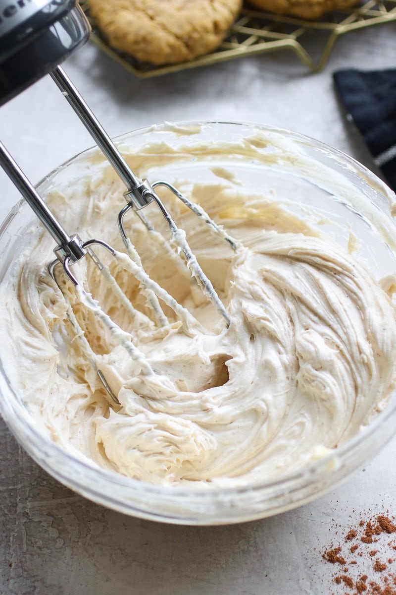 Cream cheese frosting in a glass bowl with beaters in the frosting
