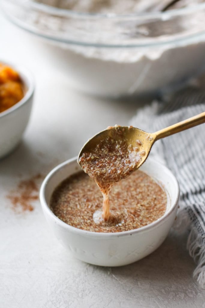 Flax egg in a small white bowl with a gold spoon stirring it