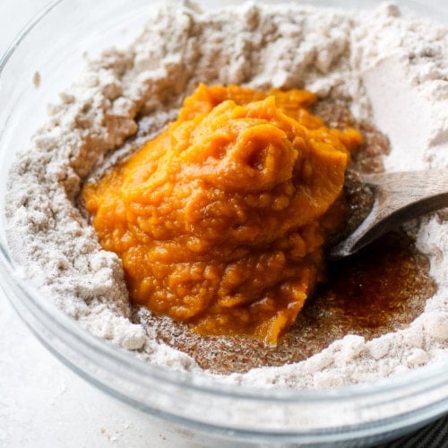 Pumpkin puree added to the cookie dough in a clear glass bowl