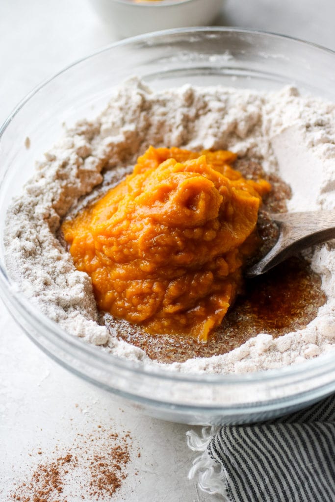 Pumpkin puree added to the cookie dough in a clear glass bowl