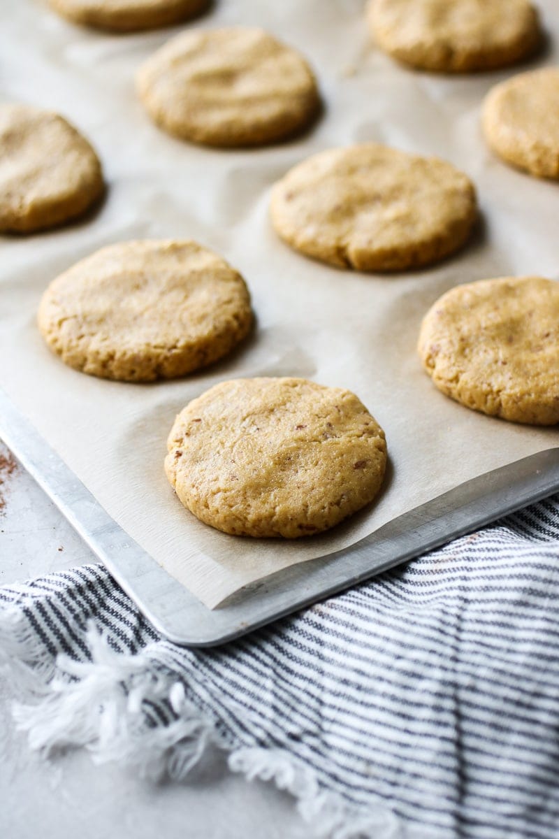 Soft pumpkin cookie dough rounds flattened on a parchment-covered baking sheet