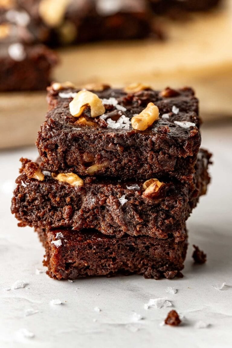 Close up view of a stack of sweet potato brownies topped with flakey sea salt and chopped nuts. 