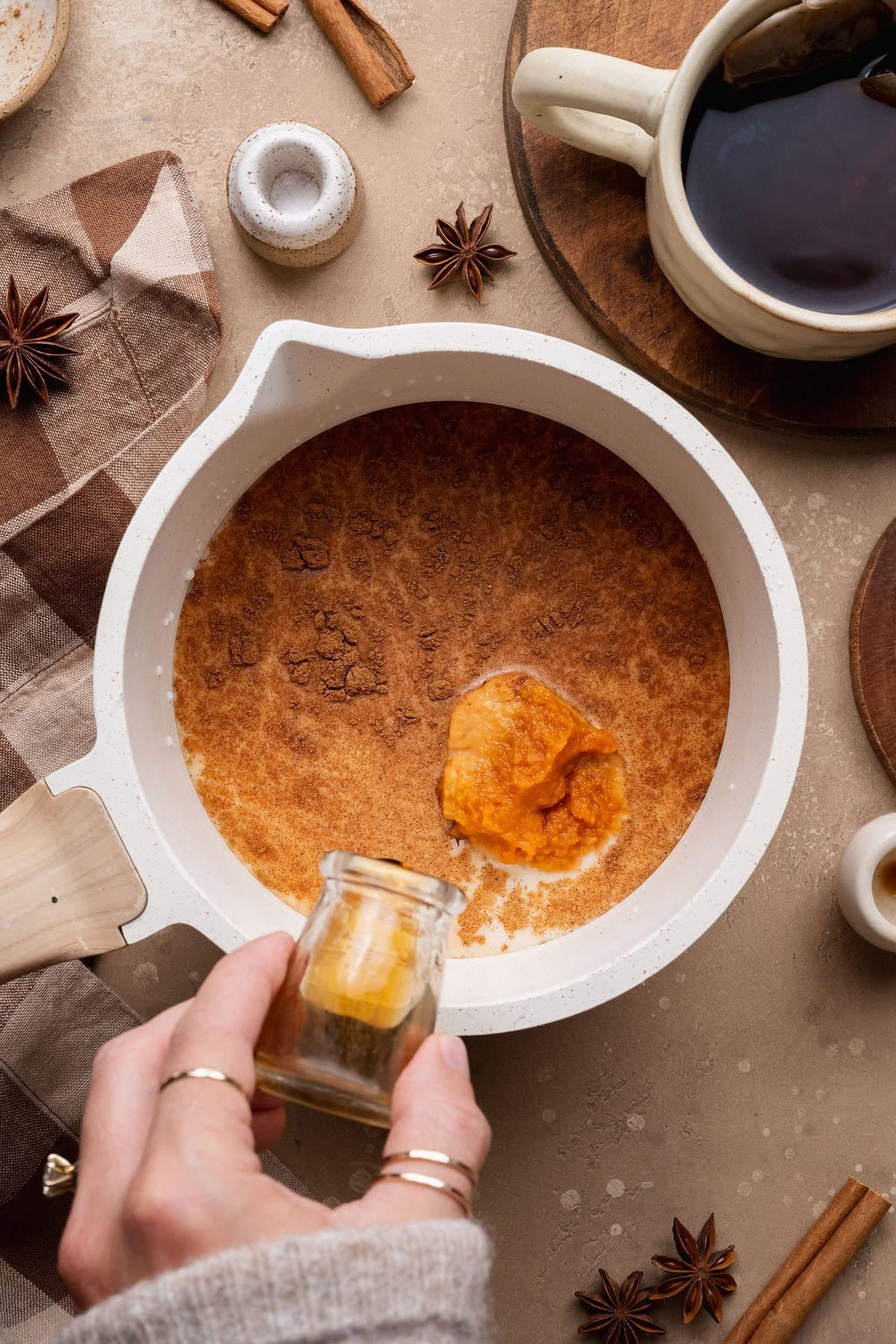 A hand mixing ingredients to make a pumpkin chai latte. 