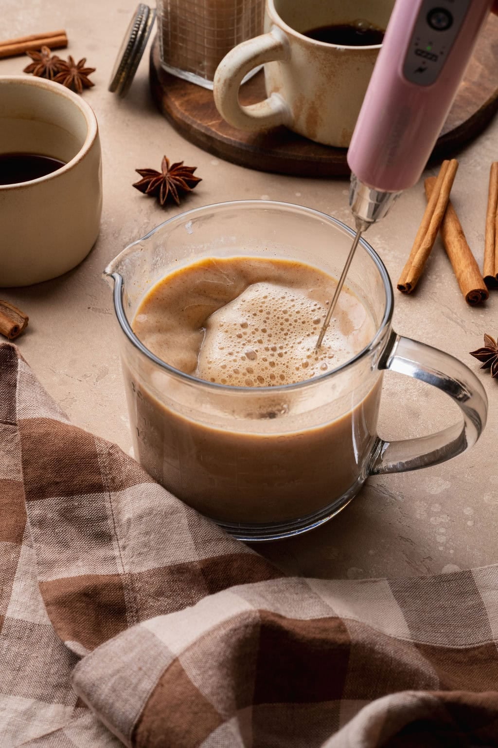 A pumpkin chai latte being frothed in a mug. 