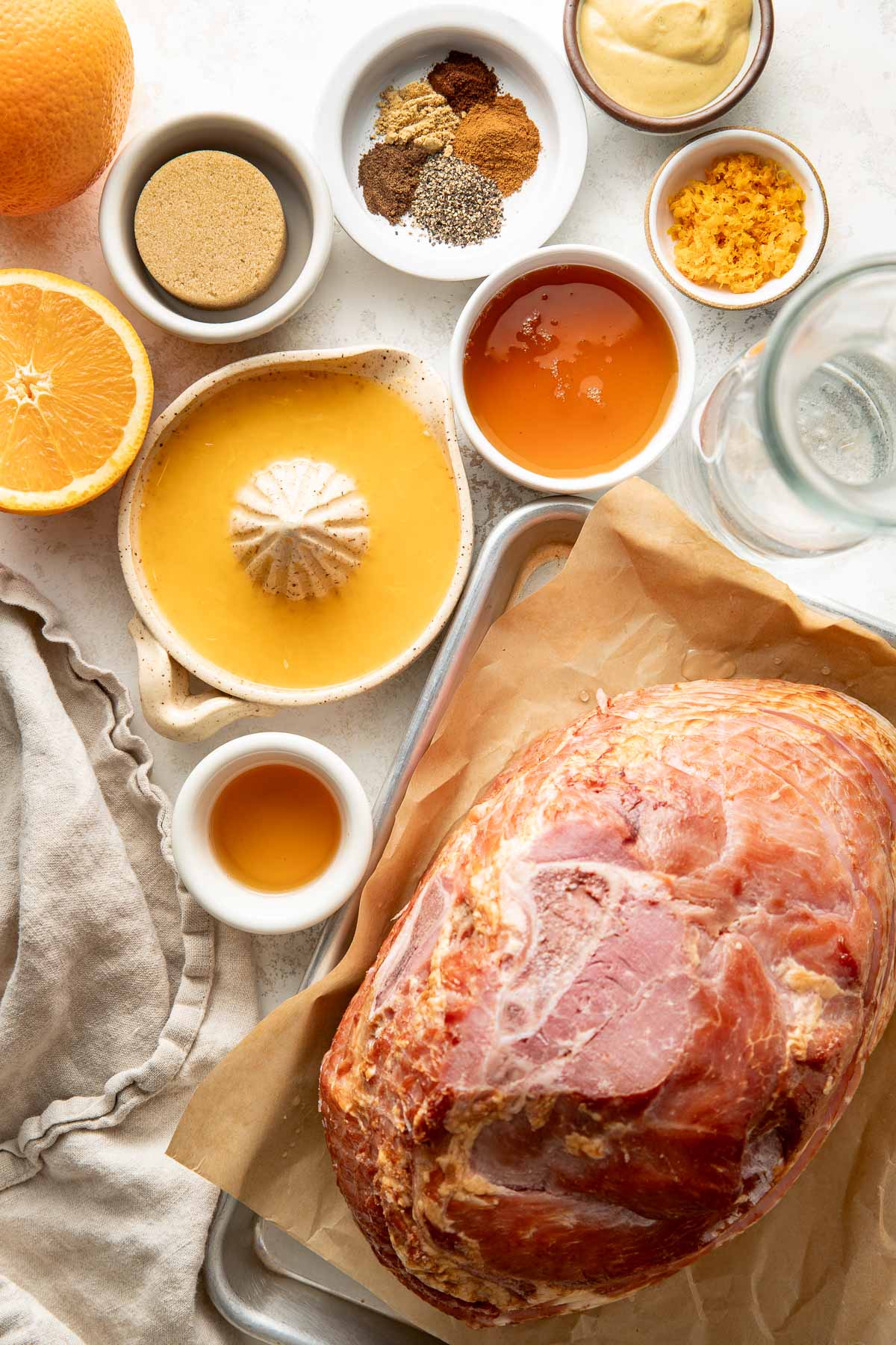 Overhead view of a variety of ingredients for Baked Glazed Ham in different sized bowls.