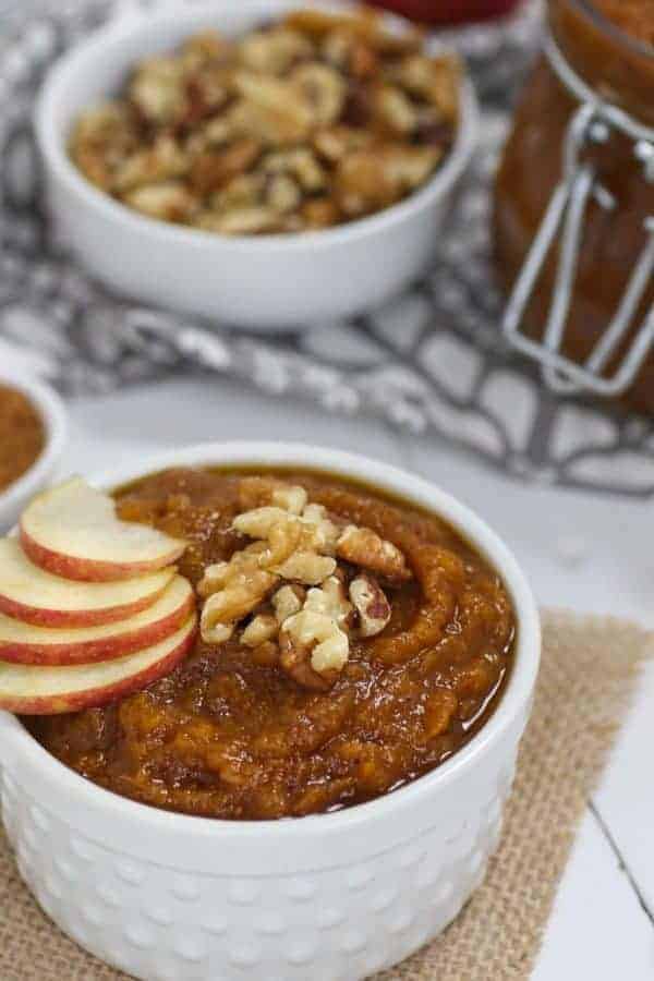 Slow Cooker Pumpkin Applesauce in a white bowl topped with apple slices and walnuts