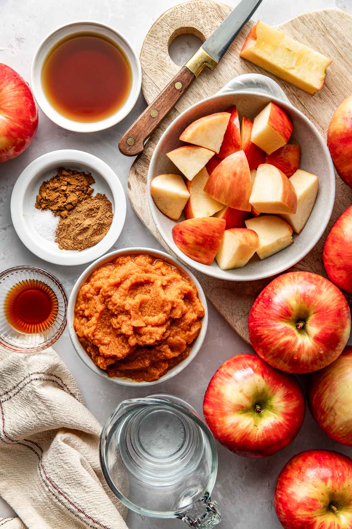 Overhead view of a variety of ingredients for Crockpot Pumpkin Applesauce in different sized bowls.