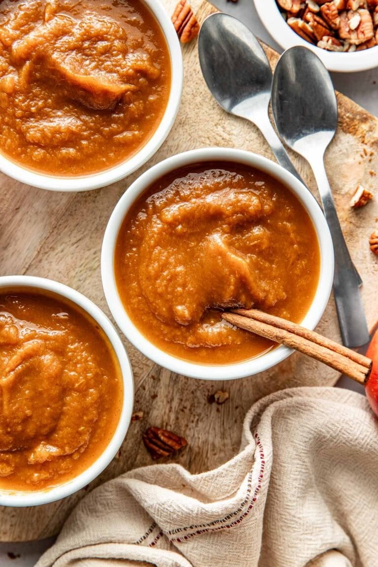 Overhead view of small bowls of pumpkin apple sauce with a cinnamon stick stuck into the bowl. 