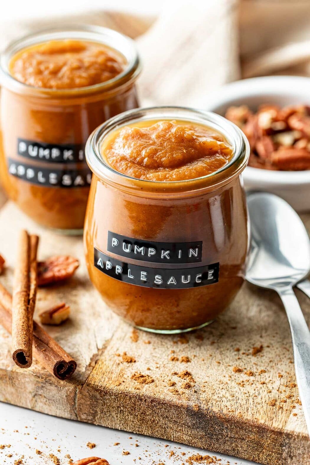 Close up view of small glass jars filled with Crockpot Pumpkin Applesauce and labeled on the front "pumpkin applesauce"