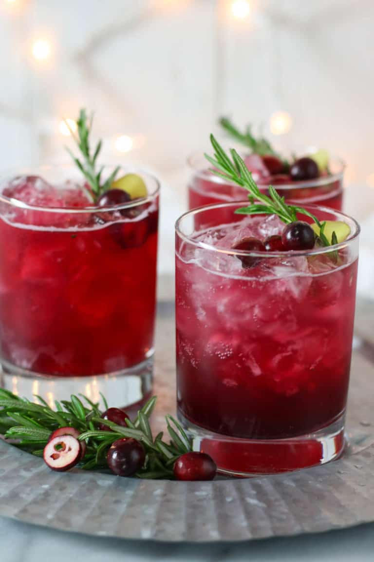 Close up view of three sparkling cranberry mocktails topped with a rosemary sprig. 
