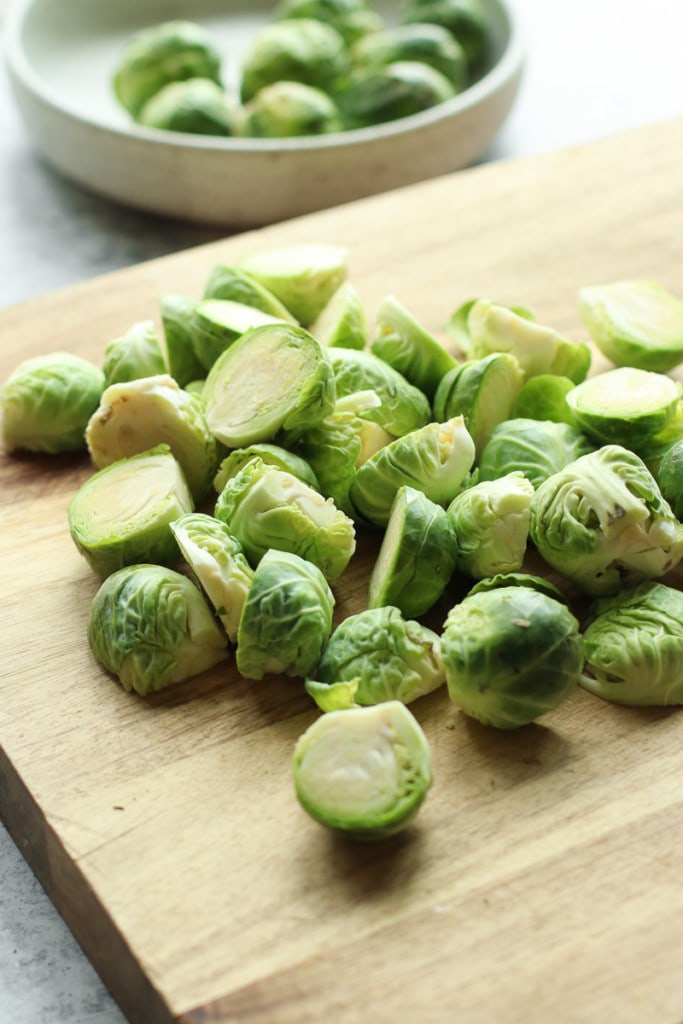 Fresh Brussels sprouts cut in half on a cutting board.