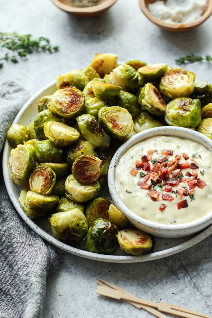 A bowl filled with fried Brussels sprouts and a portion of garlic aioli bacon.