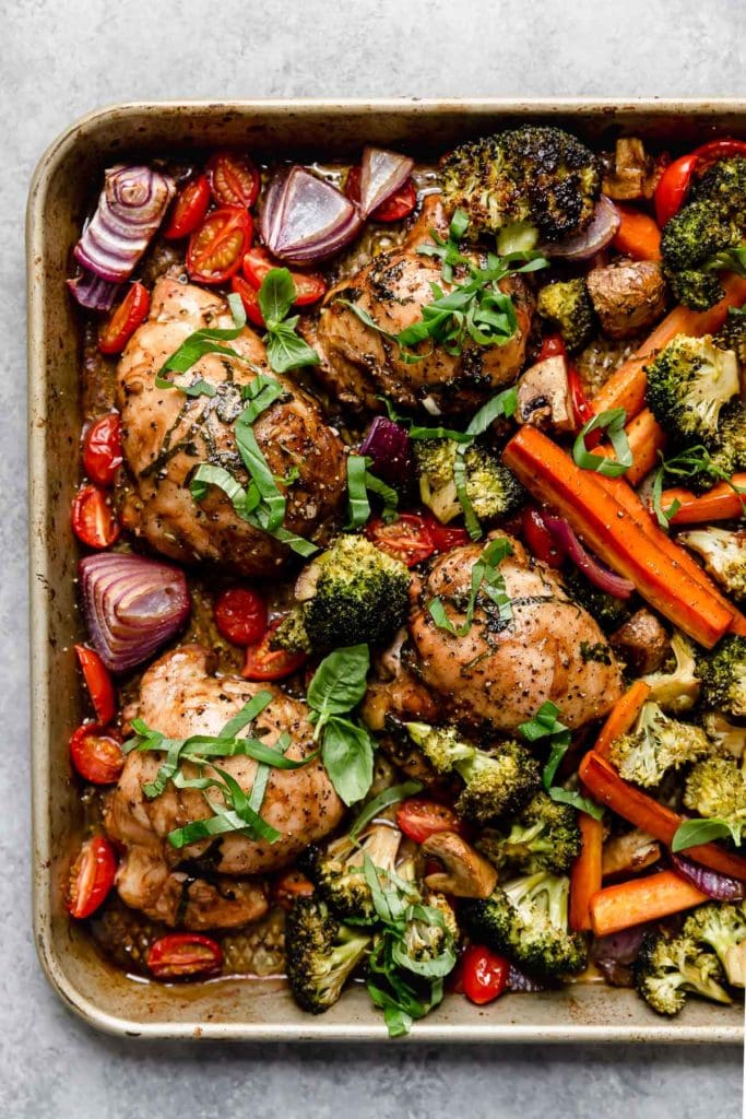Overhead image of chicken and veggies on a pan after baking in the oven.